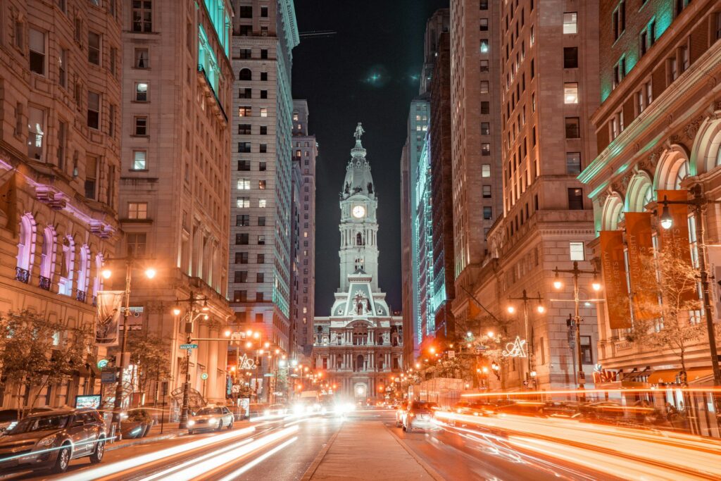 Timelapse view of Philadelphia City Hall at night from median of street with streetlights and traffic headlights.